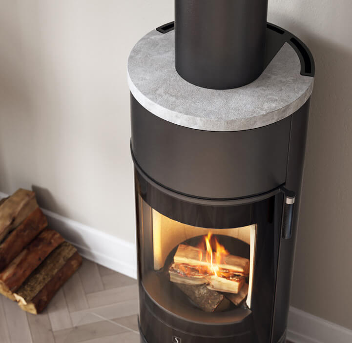 Sort peis med klebersteinstopp i lyst rom med ved på venstre side