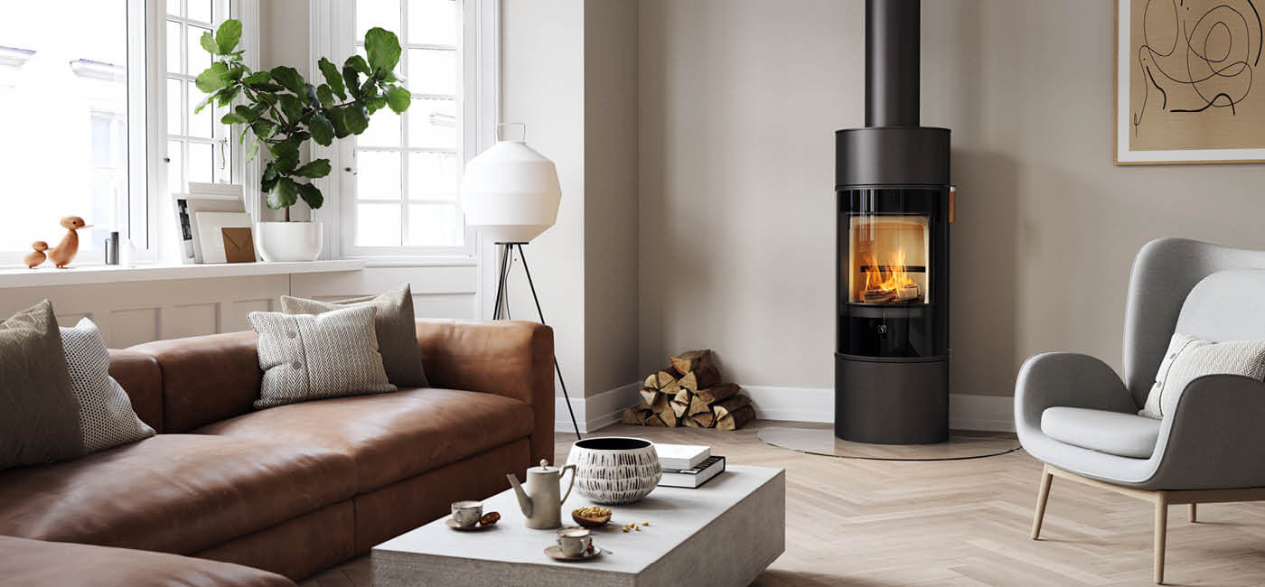 Svart rund vedovn Scan 84 Modern med sort glassdør i en klassisk dansk leilighet med lus brun skinnsofa