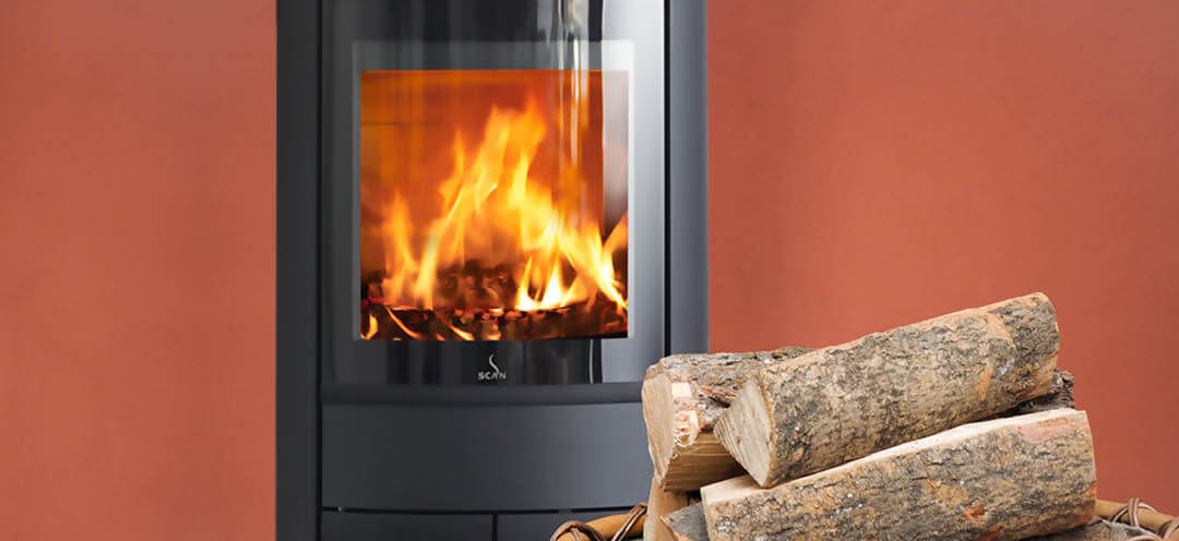 Sort oval vedovn Scan 68-13 i rødt rom med en stor kurv med ved i front