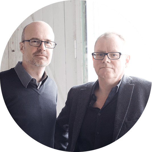 To menn i 50-årene, produktdesignerene Harrit & Sørensen, står ved vinduet i et lyst rom