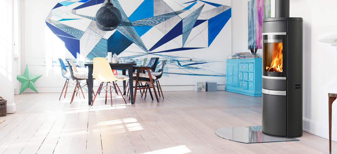 Sort oval vedovn med sideglass aluminiumshåndtak og pyntelister Scan 68-12 i hvit stue med stor grafisk kunst over spisestuen