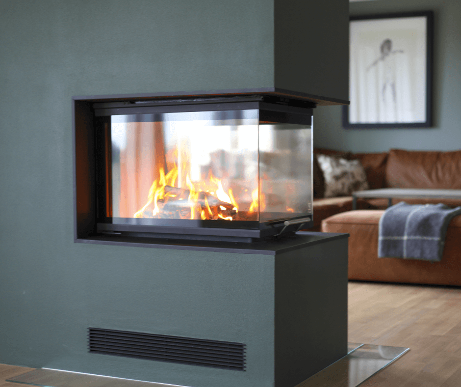 Moderne peisinnsats med glass på tre sider, integrert i en grønn vegg mellom stue og sofagruppe med brennende flammer i fokus