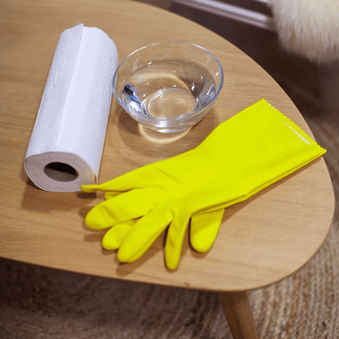 Utstyr til rengjøring av peisglass: tørkepapir, vann og gule gummihansker klart til bruk