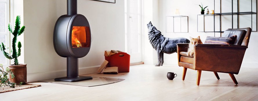 Liten vedovn eggeformet på søyle Scan 66-2 svart farge i stue med skinnstol med katt og statue av ulv 