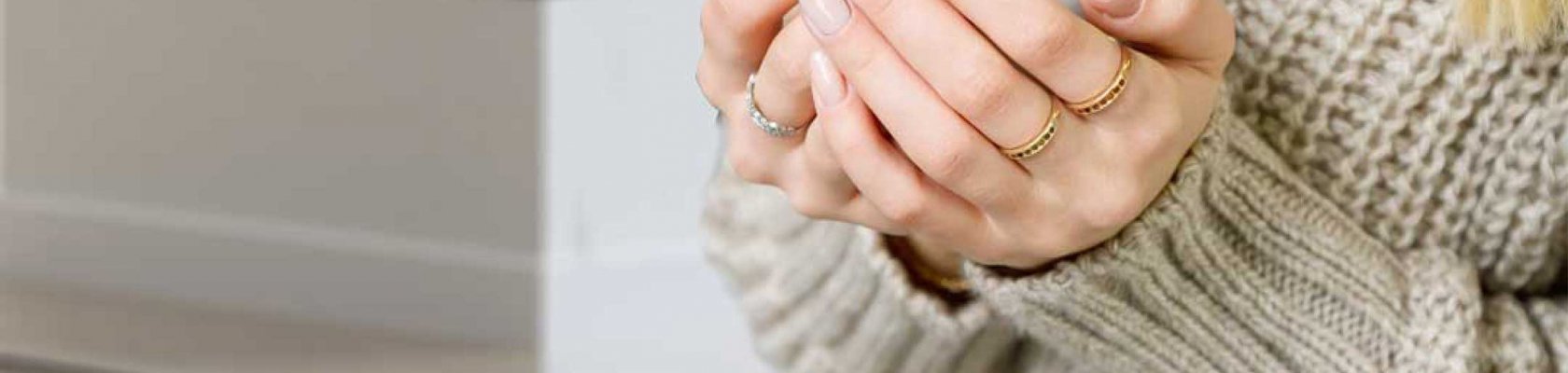 Dame med beige genser holder hvit kopp med diffus peis Scan 5005 FRL i bakgrunnen 