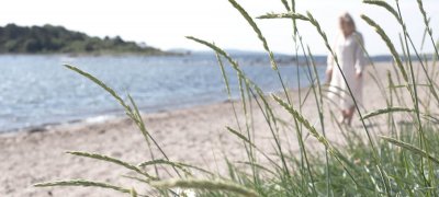 Dansk strand med en kvinne gående langs vannet