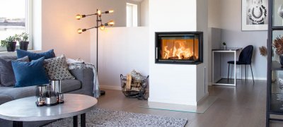 Hvit hjørnepeis med flammer i hvitt moderne hjem med grå sofa og rundt bord