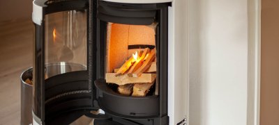 Hvit vedovn Scan 83-2 med åpen dør og bål som tennes opp