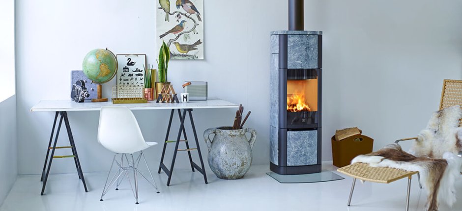 Wood-burning stove Scan 65-7 with soapstone cladding in a white office with wicker chair