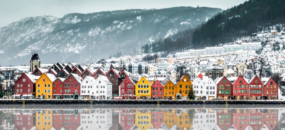 The pier in the city of Bergen in Norway in the winter with large snow-capped mountains behind
