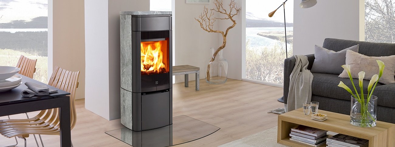 Mellomstor peisovn Scan 65-3 svart med kleberstein på sidene og stor glassdørMellomstor peisovn Scan 65-3 svart med kleberstein på sidene og stor glassdør i lys åpen stue med spisestue og lyse eikemøbler