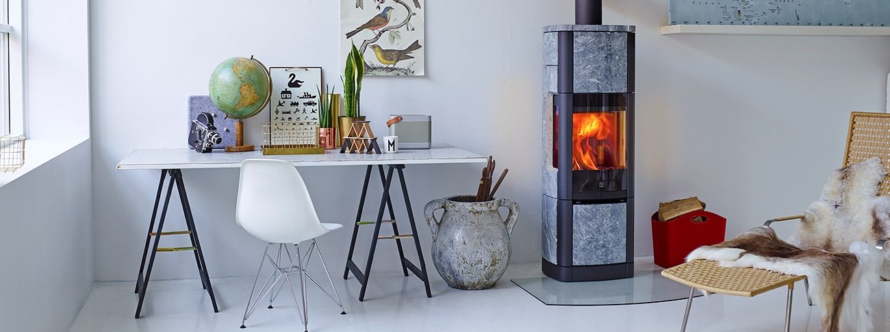 Stor peisovn Scan 65-8 High Top klebersteinsovn svart med varmelagrende kleberstein og glass på flere sider i lys stue med skrivebord 