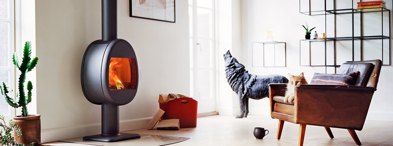 Liten vedovn eggeformet på søyle Scan 66-2 svart farge i stue med skinnstol med katt og statue av ulv