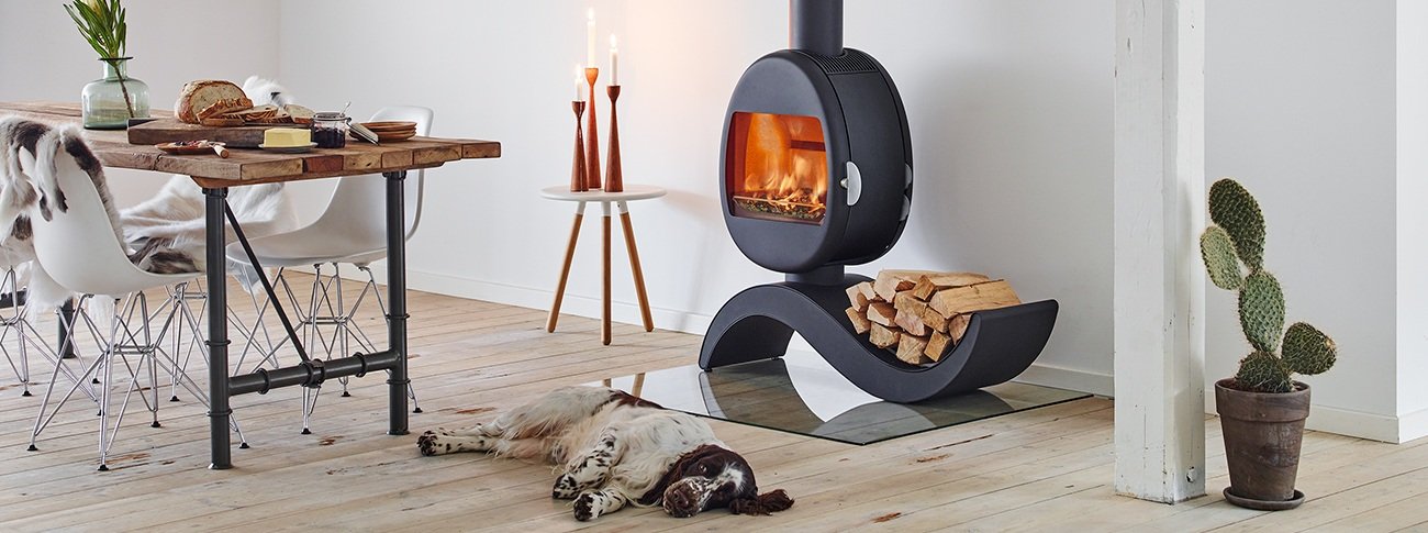 Liten vedovn Scan 66-5 eggeformet på buet base med vedoppbevaring i lys loftsleilighet med rustikke detaljer