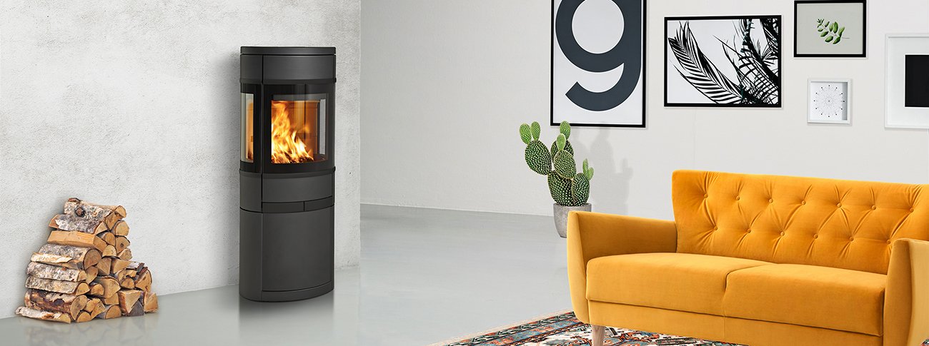 Mellomstor peisovn Scan 68-11 med glass på flere sider og eksklusive sorte glassdetaljer i industrielt mockup interiør med gul sofa