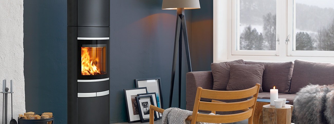 Høy peisovn Scan 68-14 High Top med stor glassdør, aluminiumsdekor mørk blå stue med store vinduer og møbler i varme fargetoner