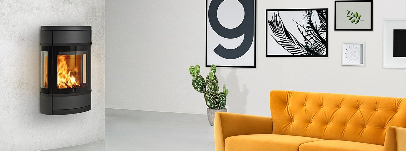 Vegghengt vedovn Scan 68-7 sort med glass på flere sider i mockup industrielt interiør med gul sofa