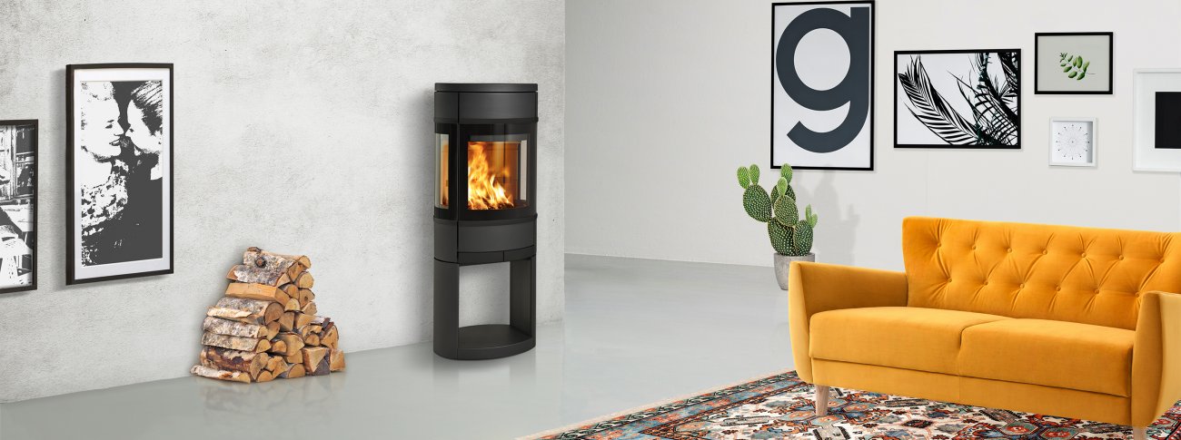 Mellomstor vedovn Scan 68-11 Open Base med glass på tre sider, eksklusive sorte dekordetaljer og åpen sokkel med plass til ved i mockup industrielt interiør med gul sofa