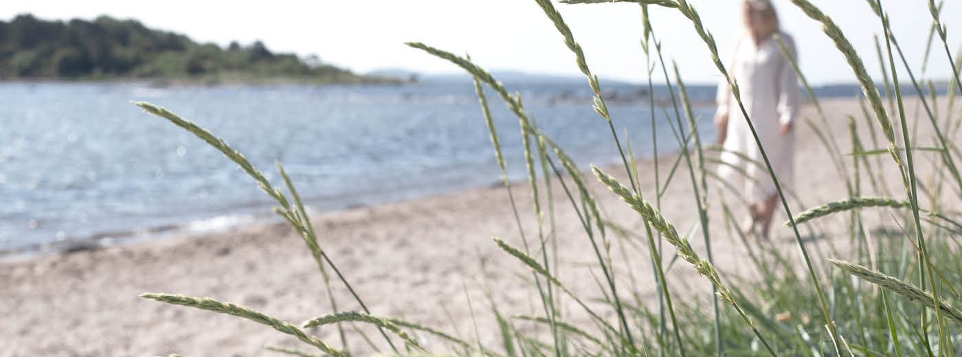 Dansk strand med en kvinne gående langs vannet