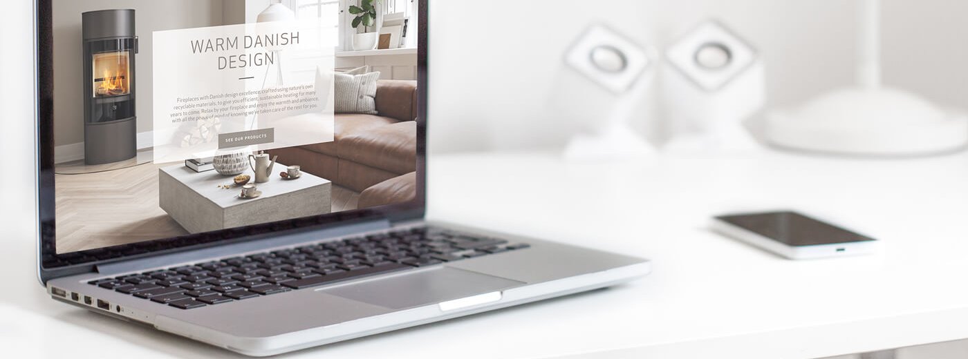 Mac bærbar med webside scan-stoves.no står på et hvitt skrivebord