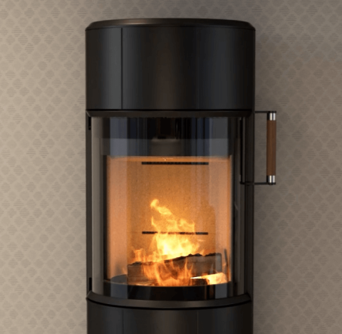 Nærbilde av sort rund vedovn Scan 67 med flammer foran vegg med beige rutete tapet