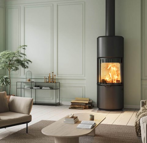 Stor sort peis Scan 87 I lysegrønt rom med lyse designmøbler, et sort konsollbord og stor plante i hjørnet